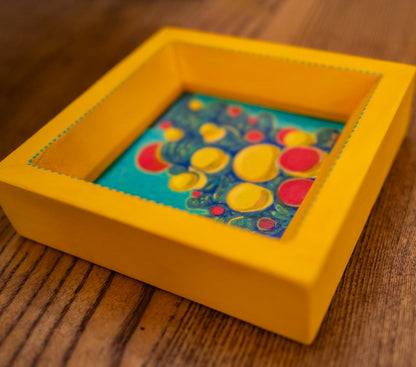 Reconnecting in its handmade, hand-painted yellow frame, lying on a wooden table.