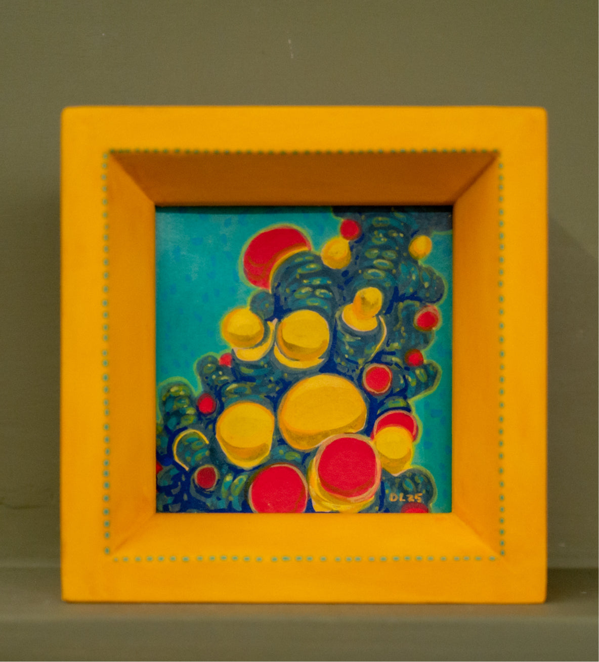 Tiny square acrylic painting of yellow and red bubbles clustered on teal and blue growth, in a handmade yellow frame with painted teal dots.